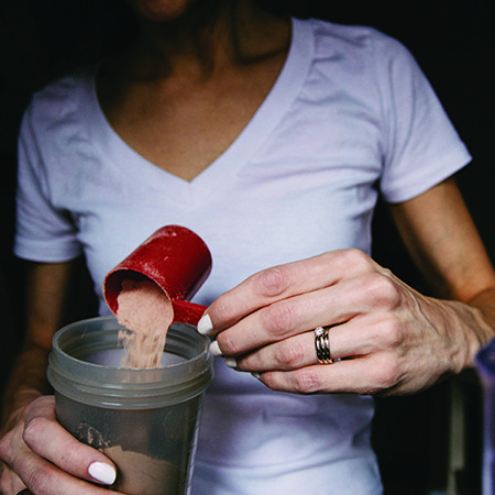 kobieta przygotowująca odżywkę białkową w shakerze